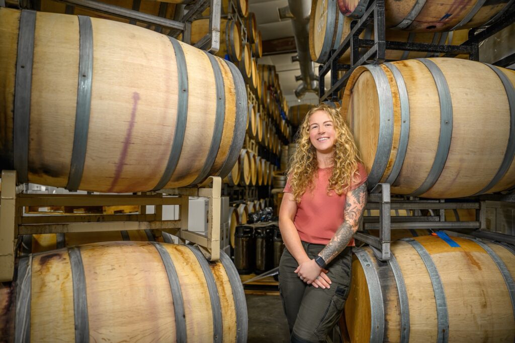 Cassidi Harris stands in a room full of wine barrels.