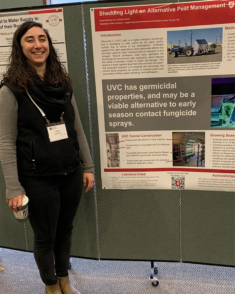 Smiling student standing adjacent to a scientific poster.