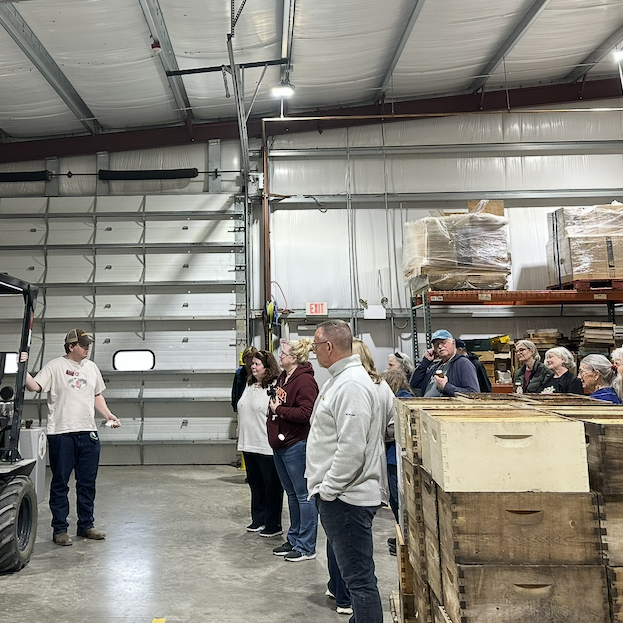 A group of people listening to a presentation in a warehouse.