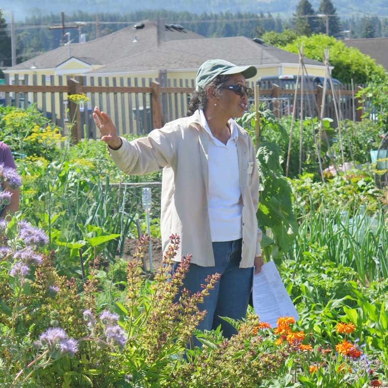Person speaking and gesturing in a flower garden.
