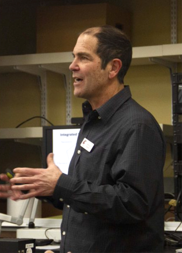 Man in dark shirt and WSU name tag speaking and gesturing.