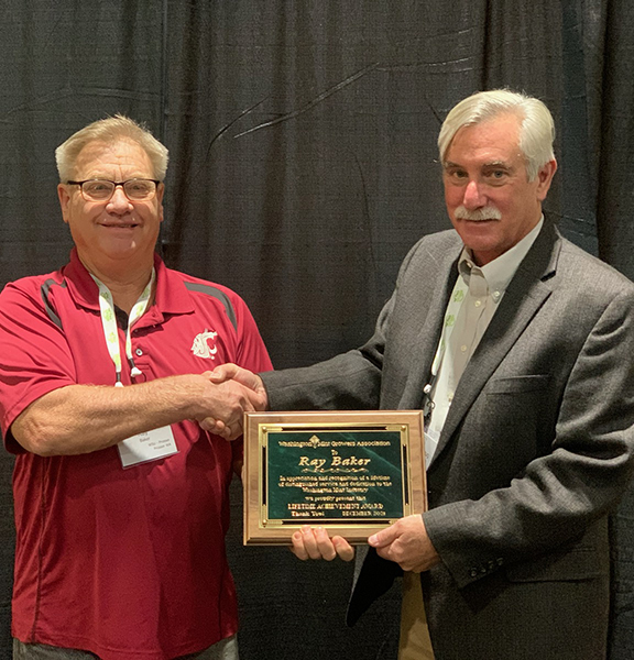 Two men holding an award plaque and shaking hands.