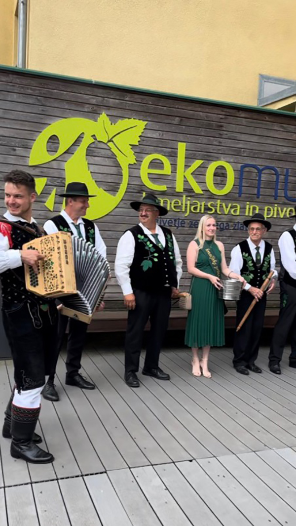 Seven people with musical instruments and traditional costumes in front of a building.