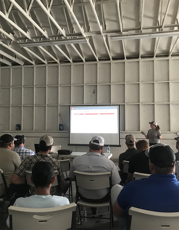 Group of people in folding chairs watching a PowerPoint presentation in a warehouse