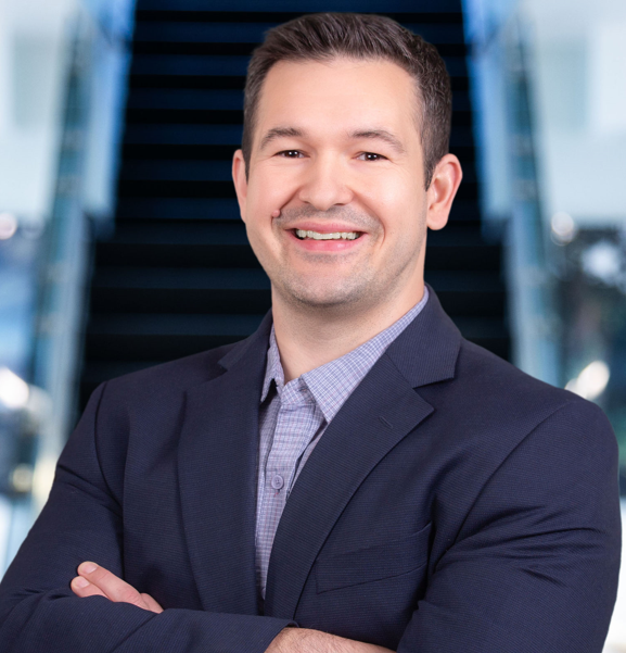 JIm Chapa headshot:  Jim standing in front of a stairway.  He is wearing a blue suit.