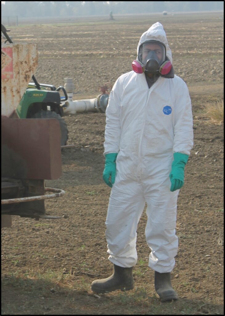 Woman in protective gear with respirator in a field