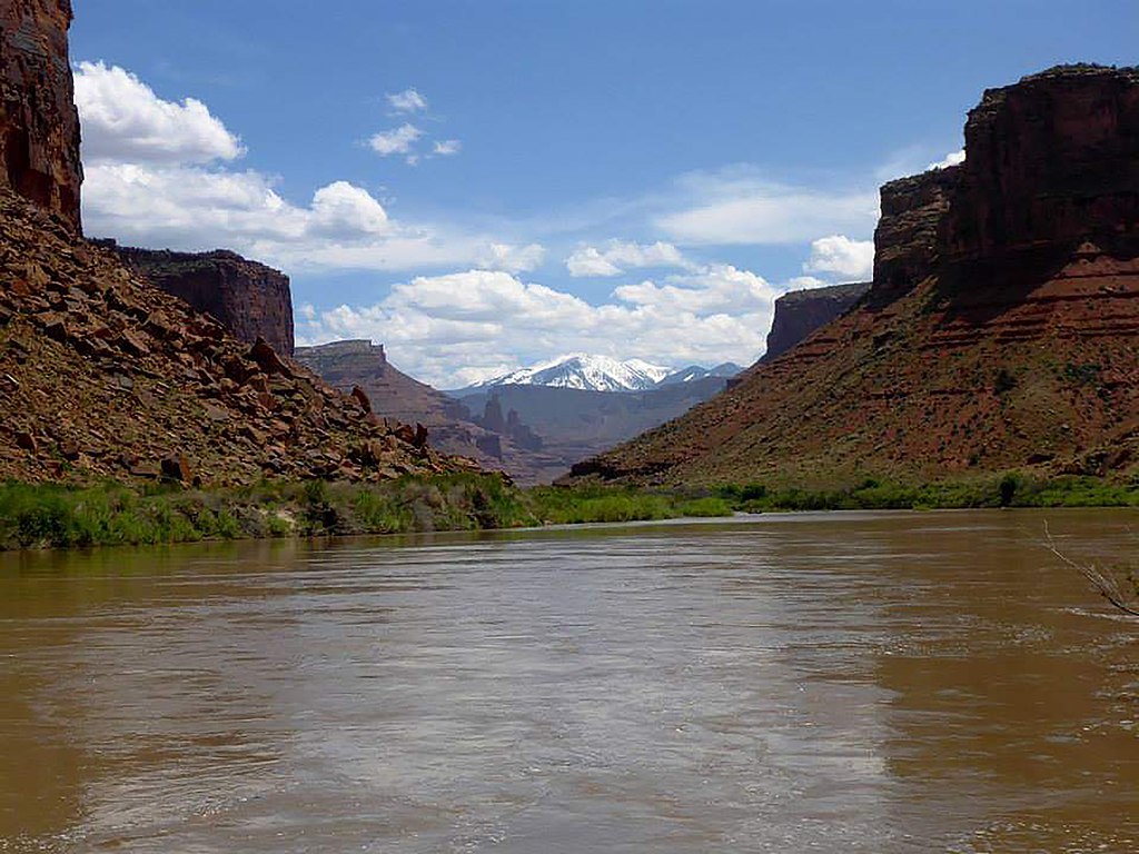 River flowing between buttes with snow-capped mountains in the background