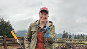 Woman holds bone from offal compost heap.