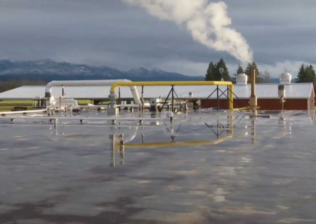 View of anerobic digester with snowy mountains and cloudy skies in the background.