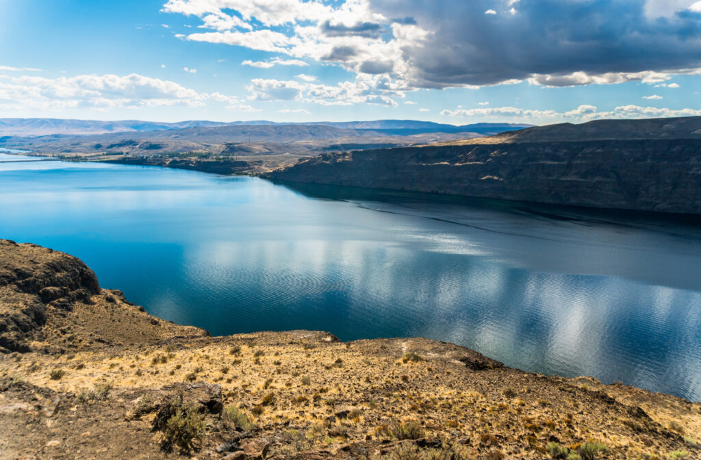 Columbia River in arid landscape on partly cloudy day.