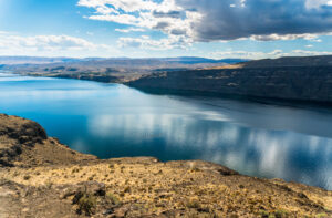 Columbia River in arid landscape on partly cloudy day.