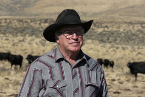 Portrait of rancher, with cattle on the range in the background