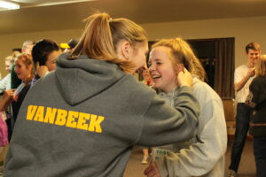 Two teen girls smiling and touching each others ear.