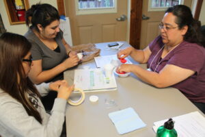 An adult and two youths sitting at a table.