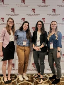 Four people smiling at camera, one holding an award.