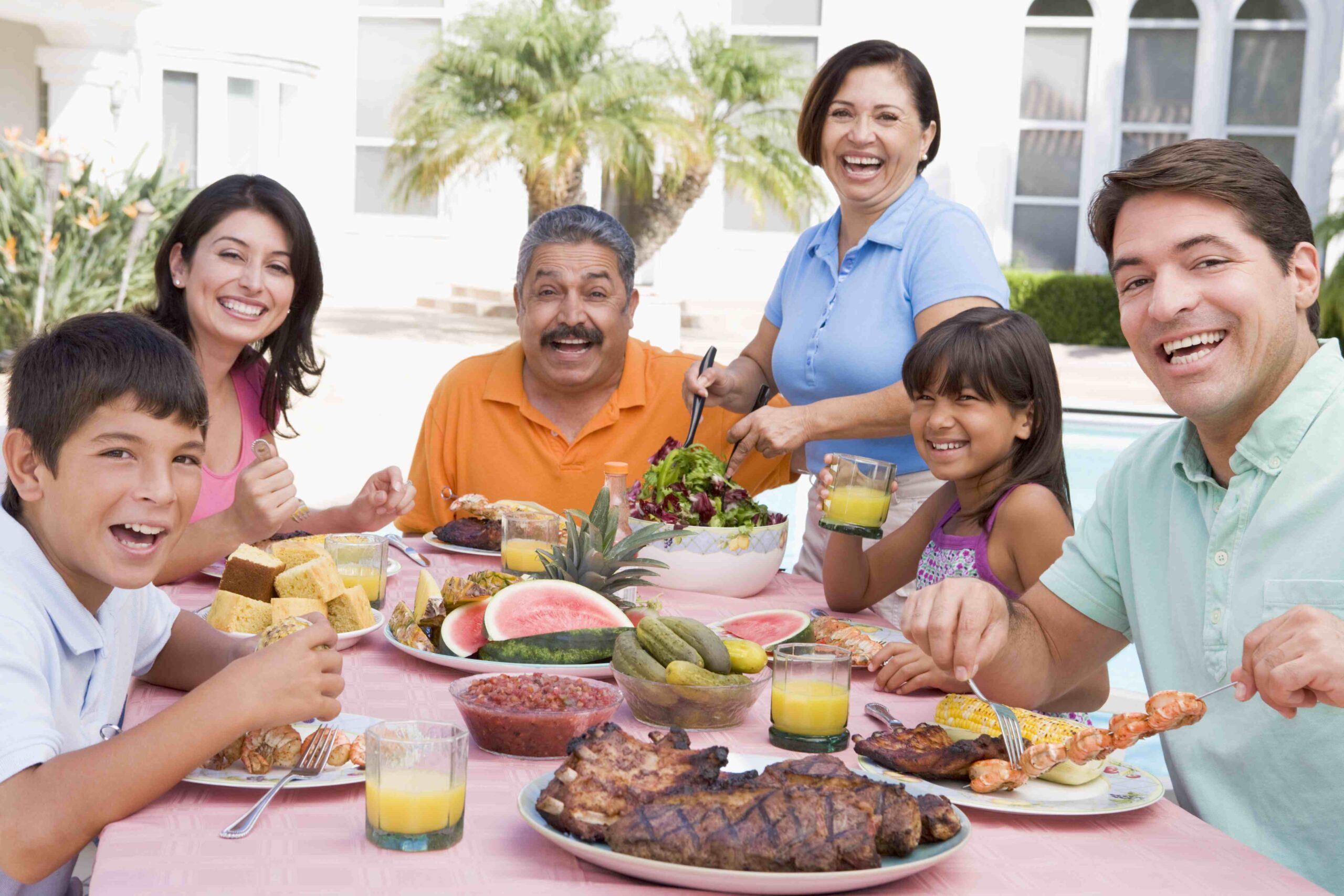 Latino extended family eating a meal together outside.