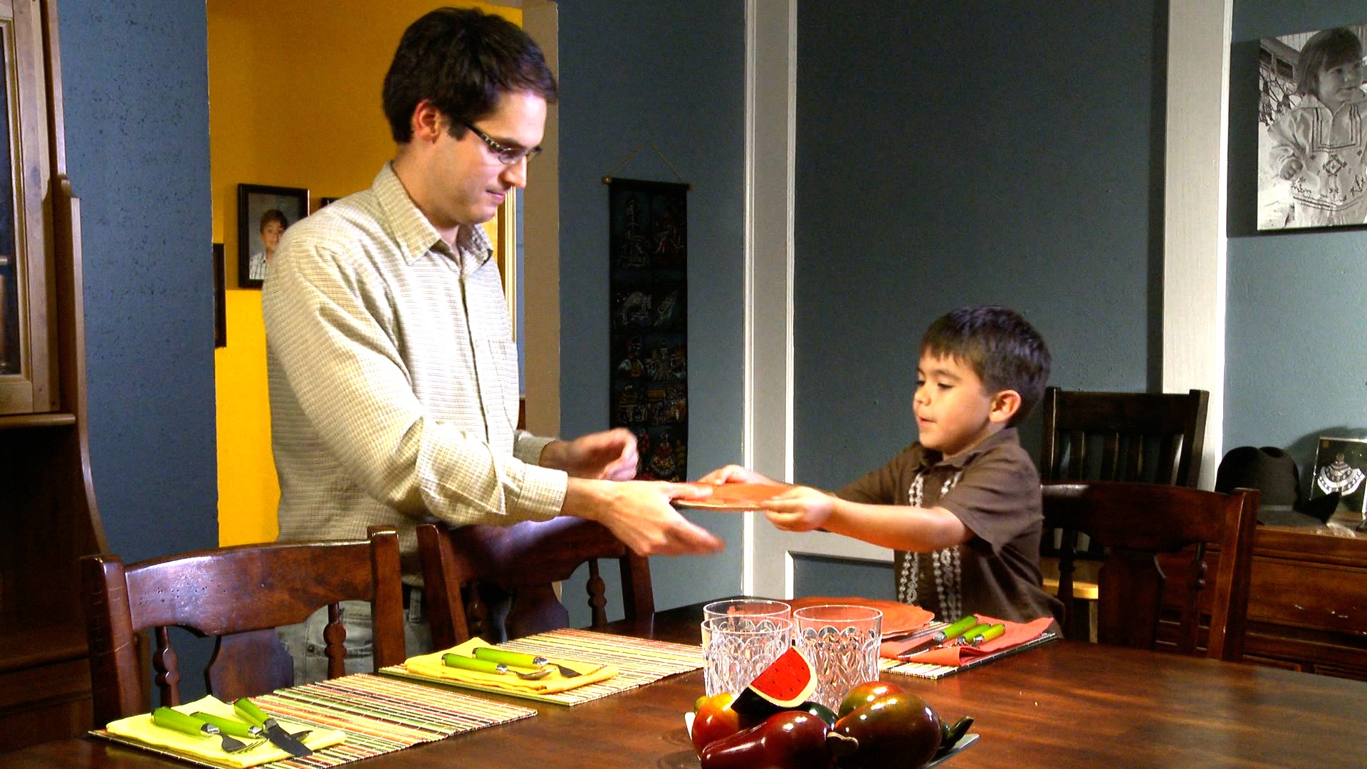 Child helping father set table.