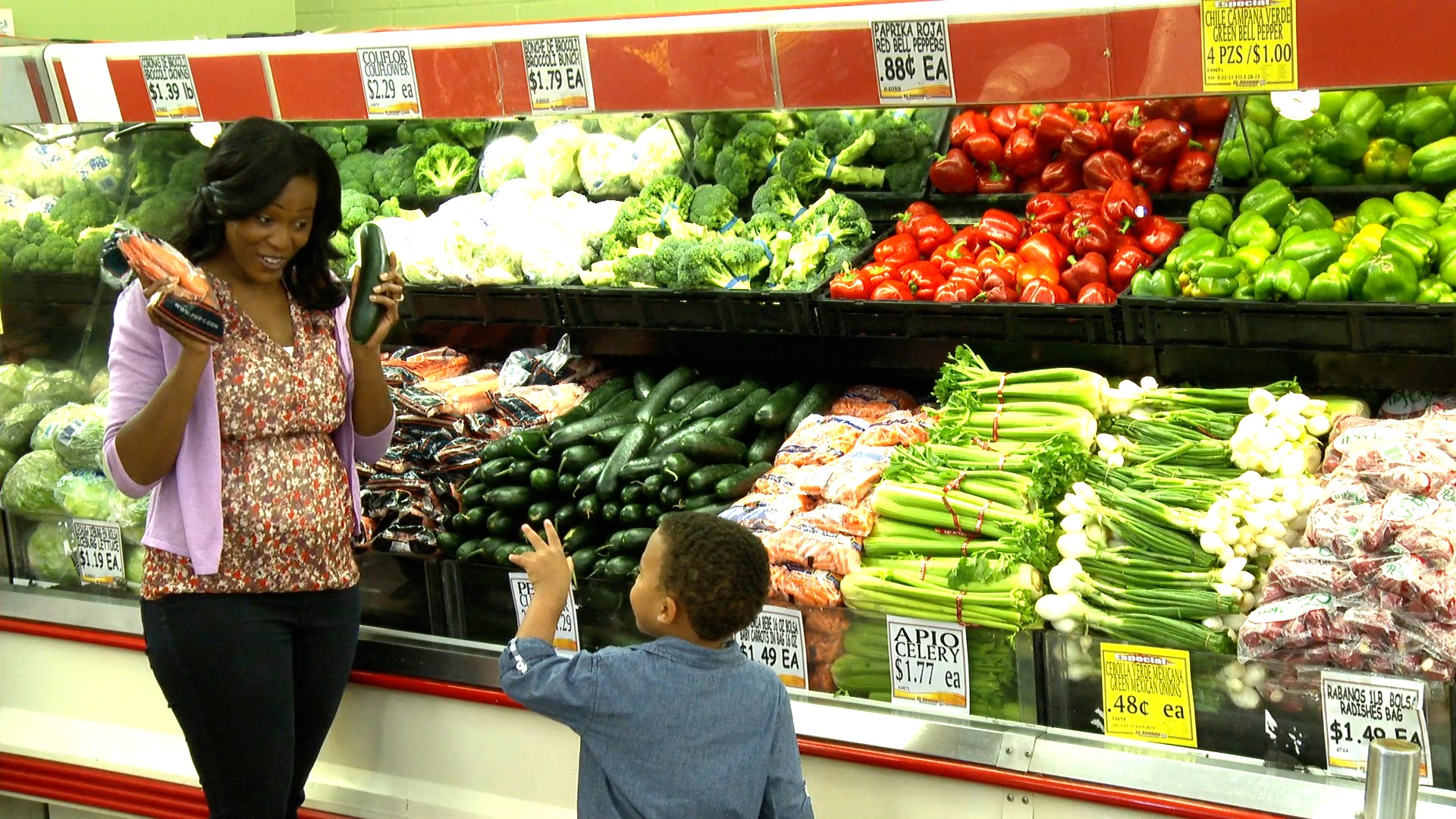 Mother shopping with young child in the produce section.