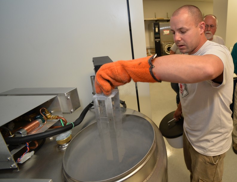 Brandon Hopkins pulling rack out of a liquid nitrogen tank