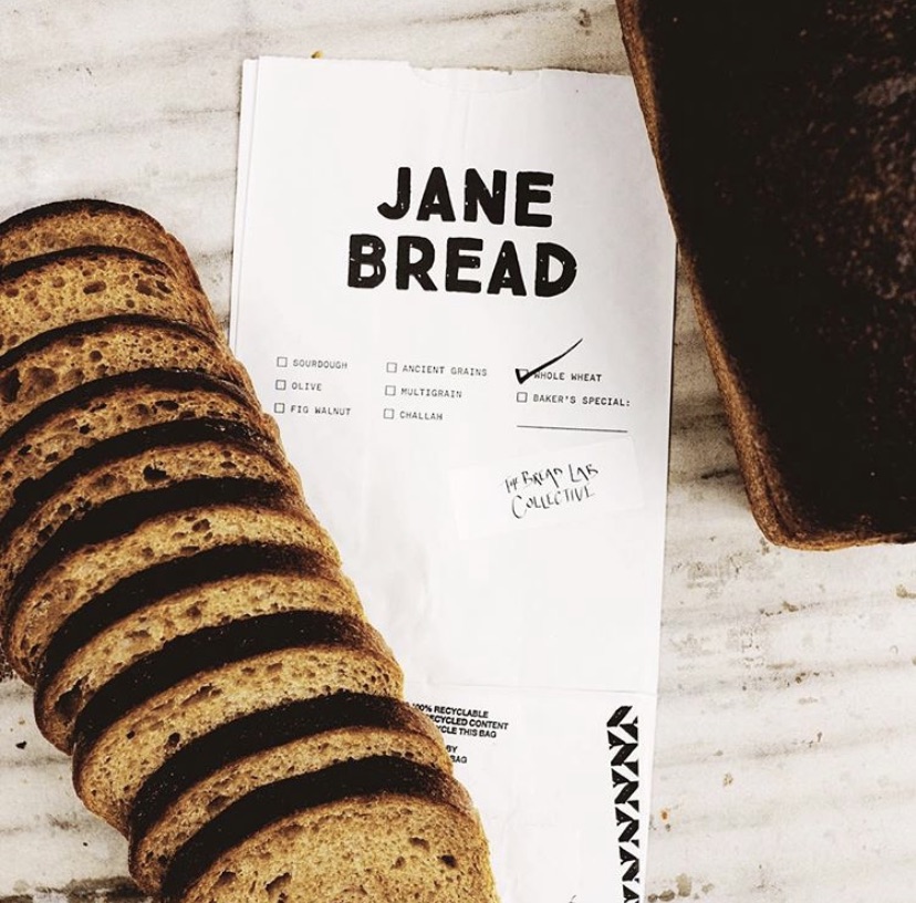 Sliced break next to a white piece of paper that reads Jane Bread with Whole Wheat checked. 