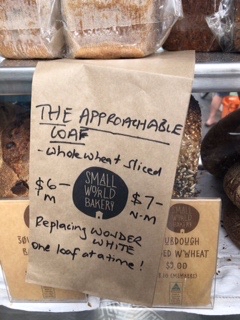 Sign that reads The approachable loaf, whole wheat sliced, $6 m, $7 NM, replacing Wonder White one loaf at a time. 