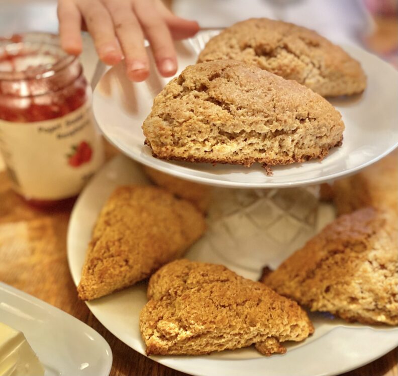 child's hand reaching for a scone on a tiered tray