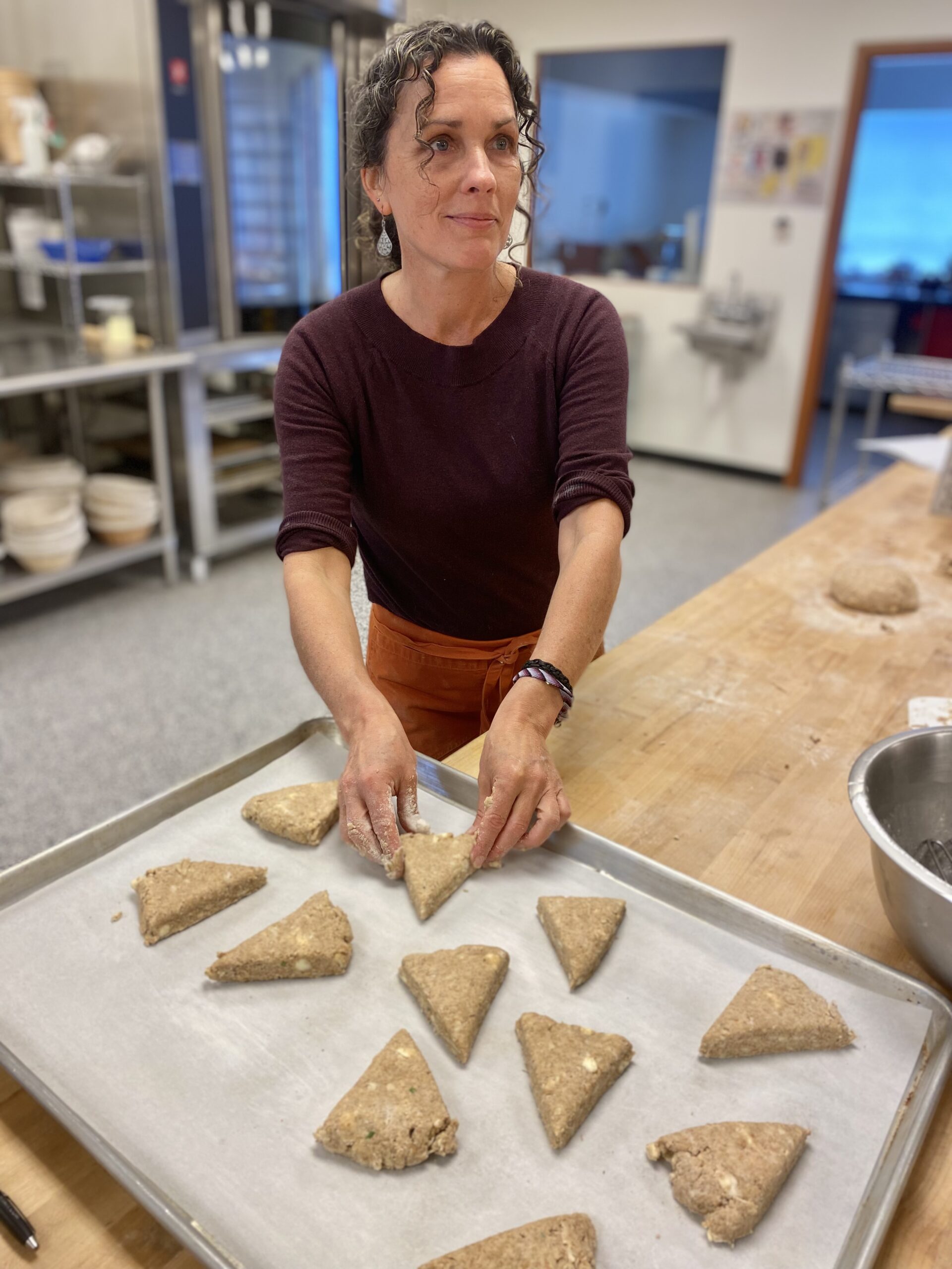 Woman arranging scones on a baking sheet.