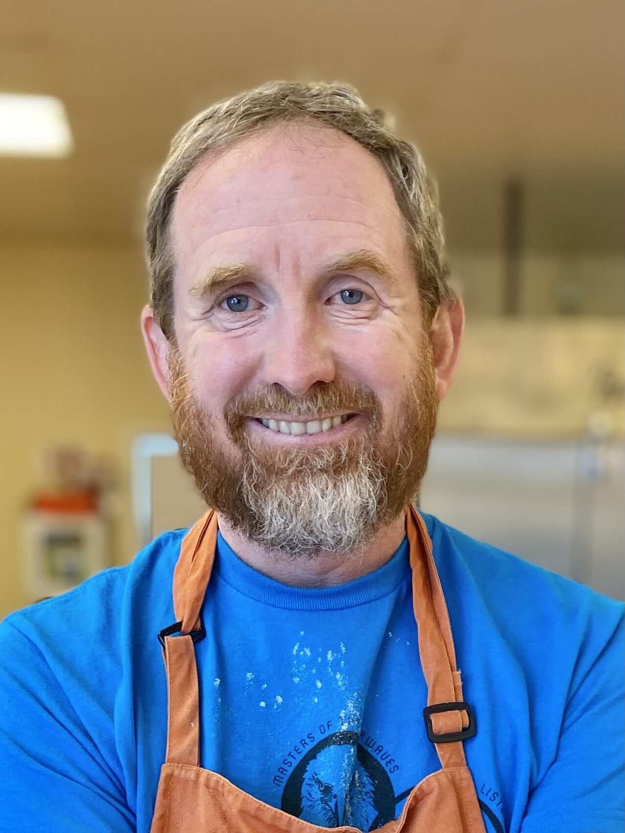 man wearing a blue shirt and orange apron smiling