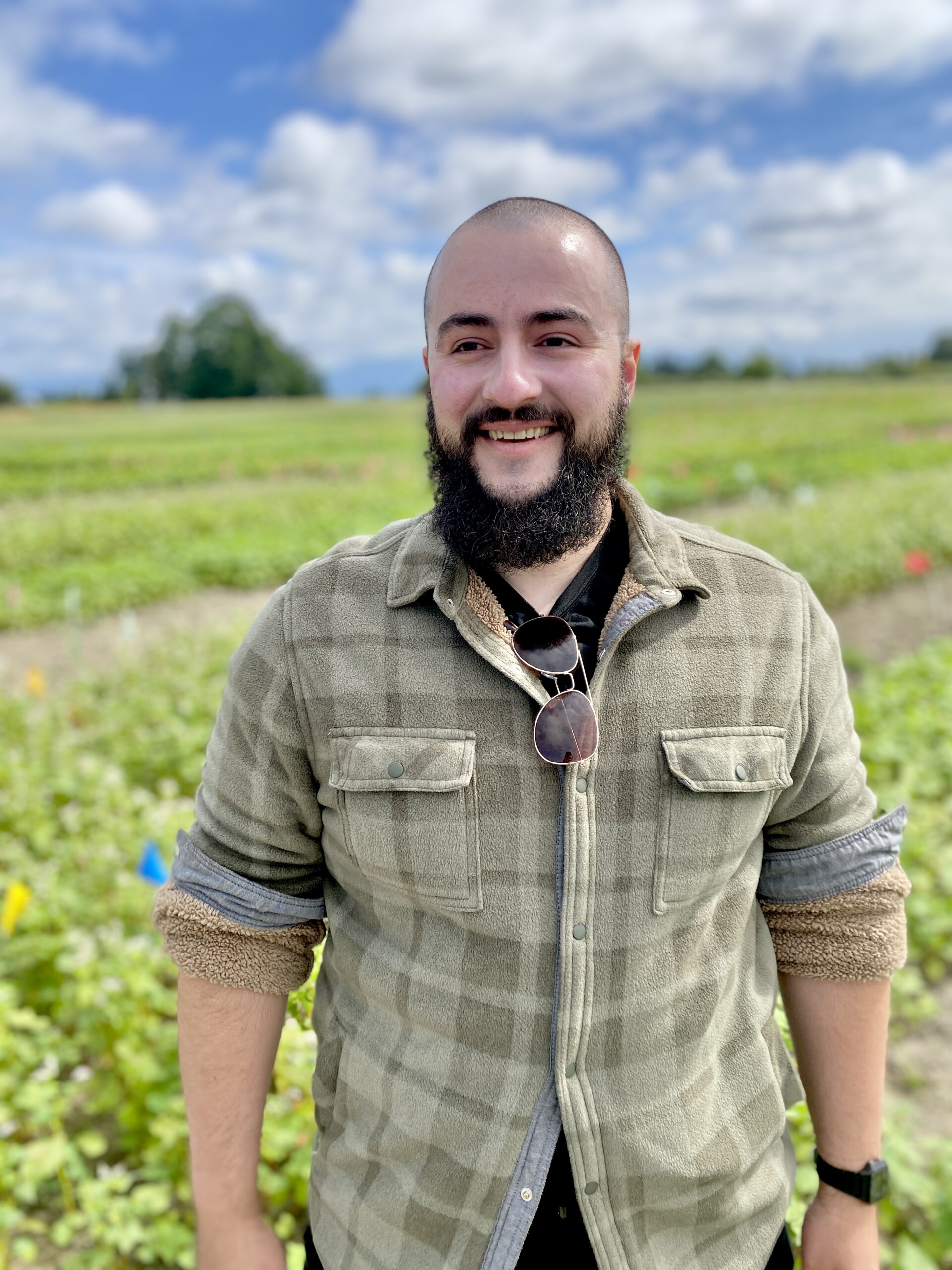 Man standing in front of a field smiling.