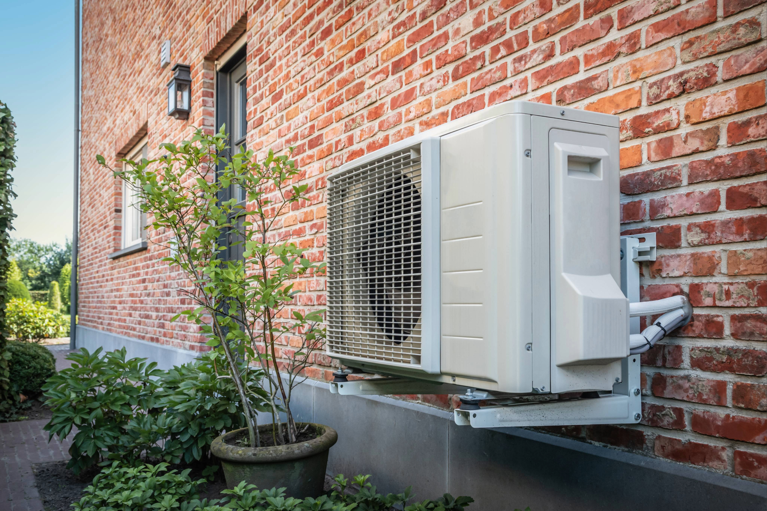 Air to air heat pump for cooling or heating the home on the side of a brick building.