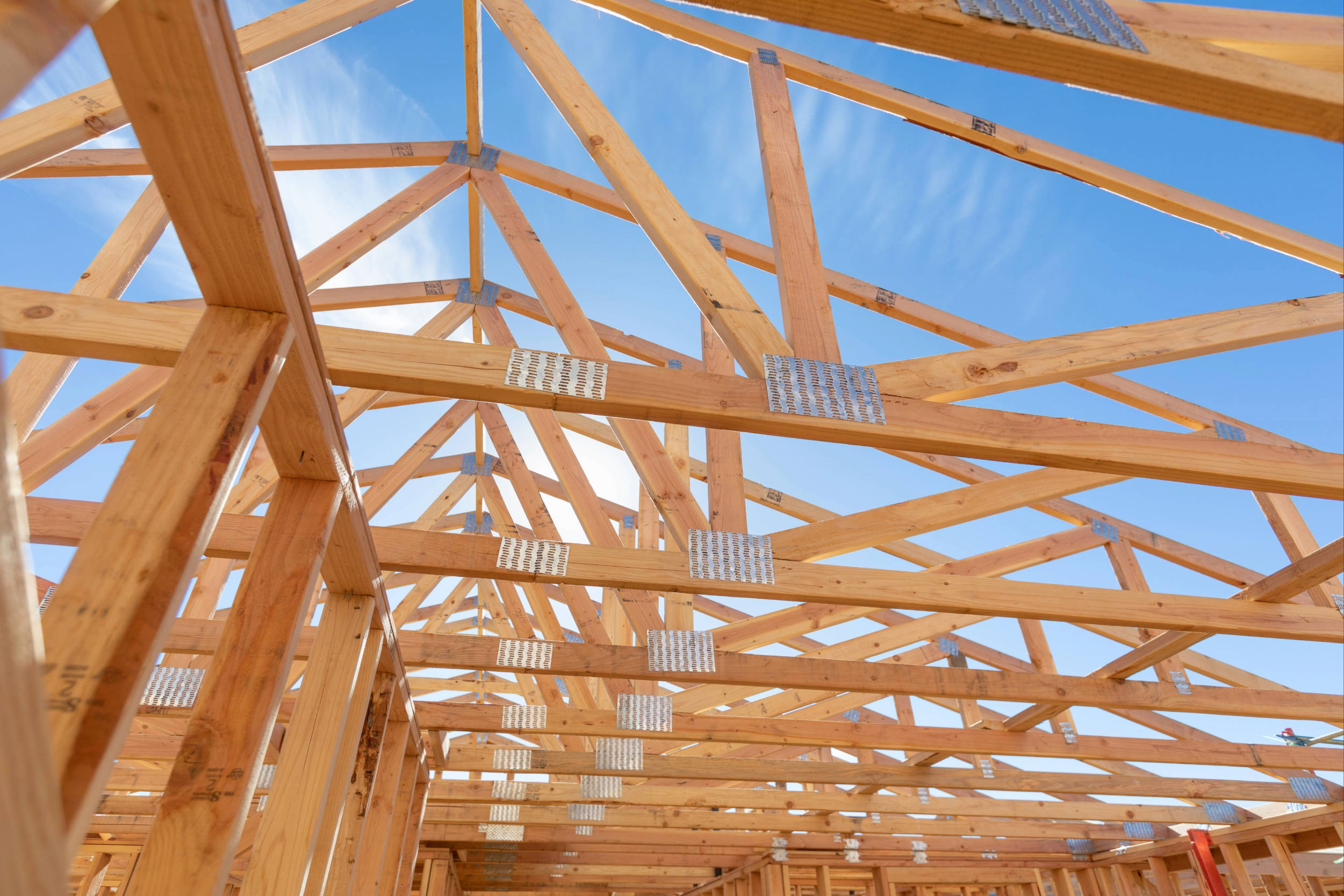 An unfinished, framed roof. A blue and sunny sky in the background.