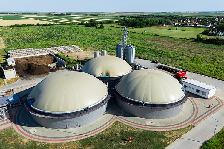 Aerial view of biogas plants with three digesters before a green field