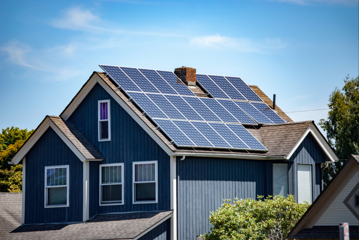 A blue multi-level home with solar panels covering the roof