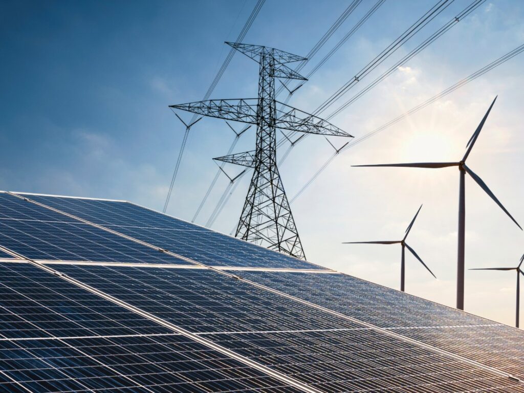 An image of solar panels, power lines, and wind energy in front of a blue sky.