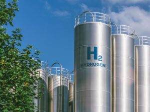 Hydrogen tanks labeled "H2 Hydrogen" sit in front of a blue sky.