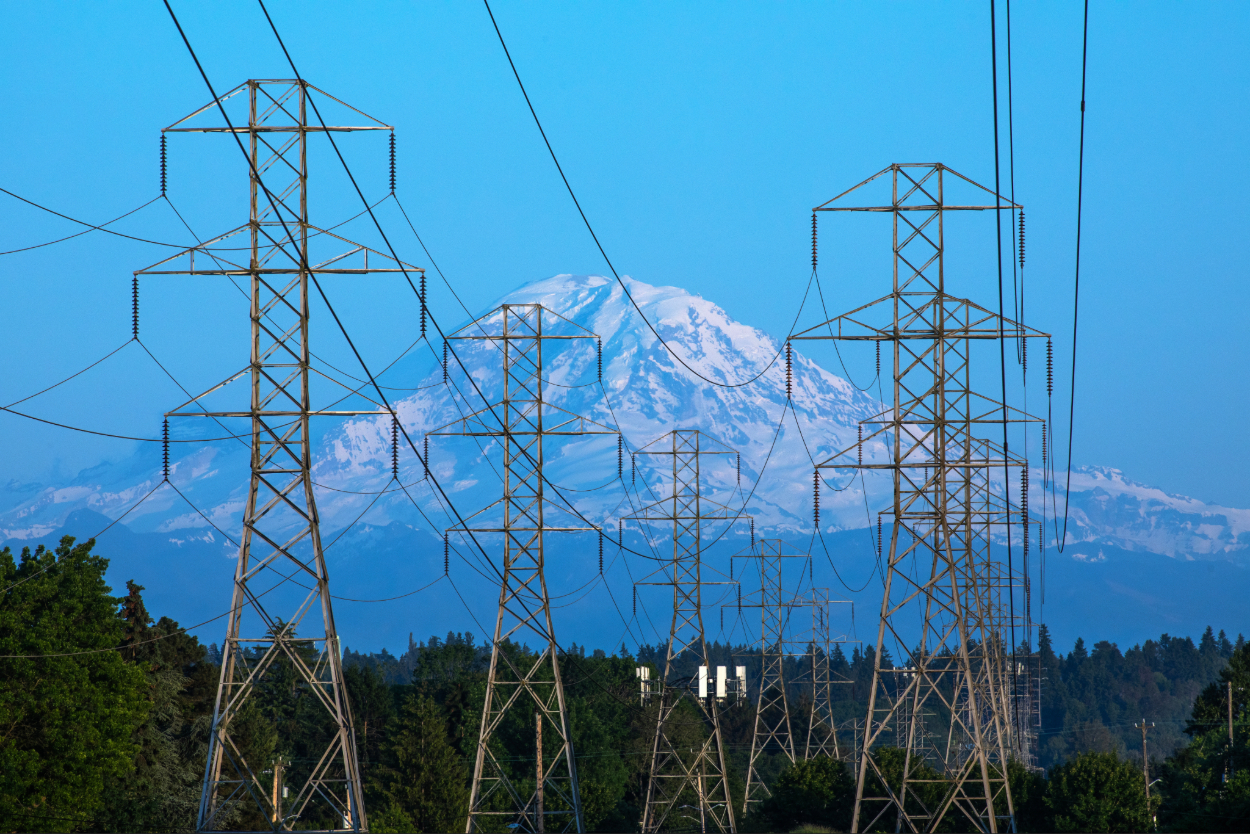 Electrical transmission lines towering in front of a distant Mount Rainier in Seattle, Wash.