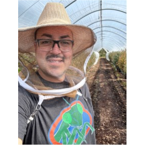 A smiling man with a hat in a filed
 