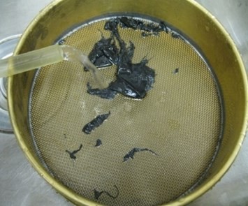 Running water over mulch fragments in a round sieve.