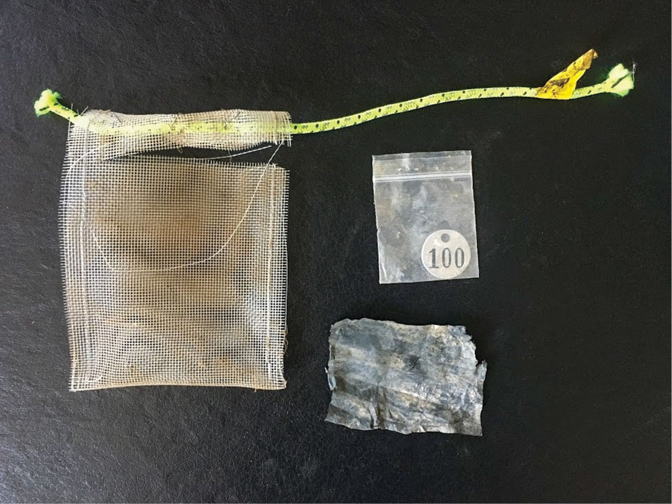 Mesh bag with mulch sample and aluminum tag.