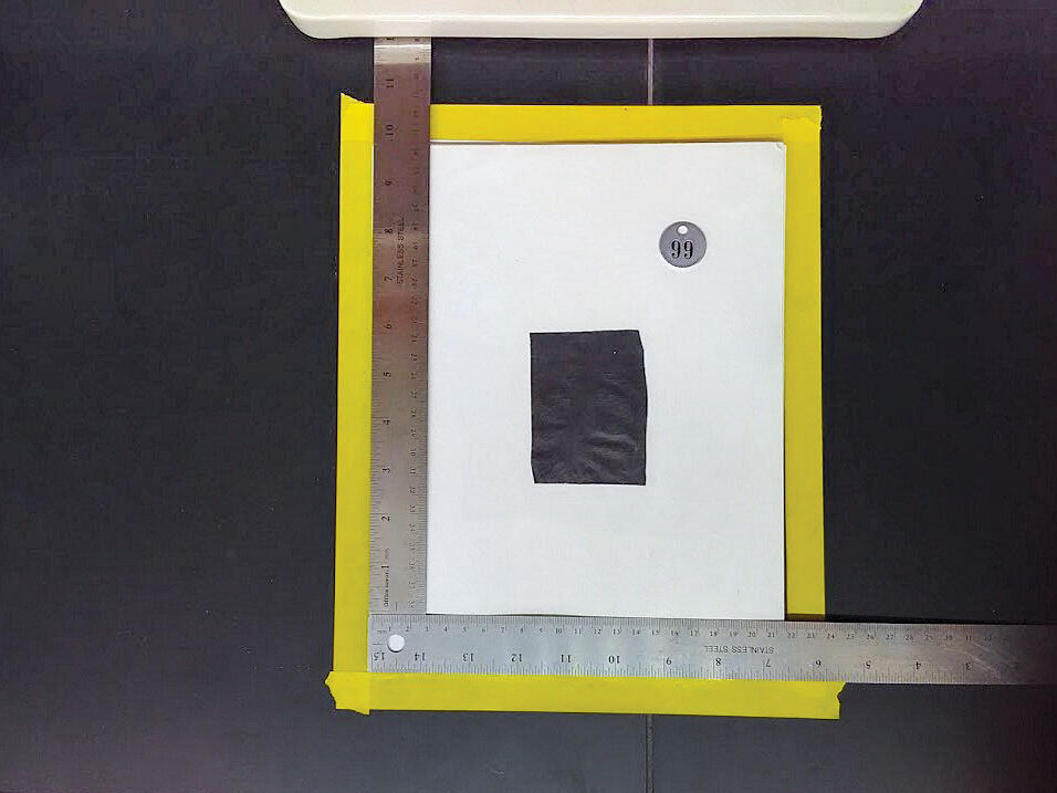 Mulch sample and tag on white paper with two rulers placed perpendicularly to each other for scale.