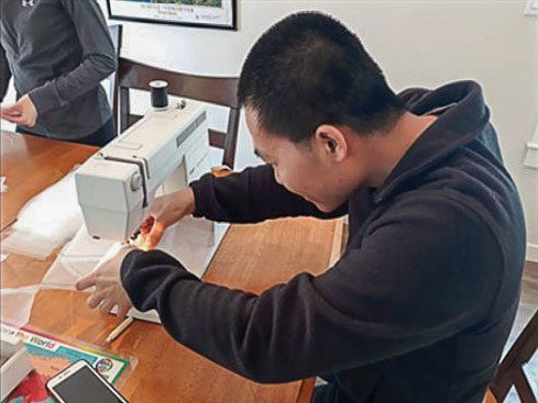 A young man working at a sewing machine.
