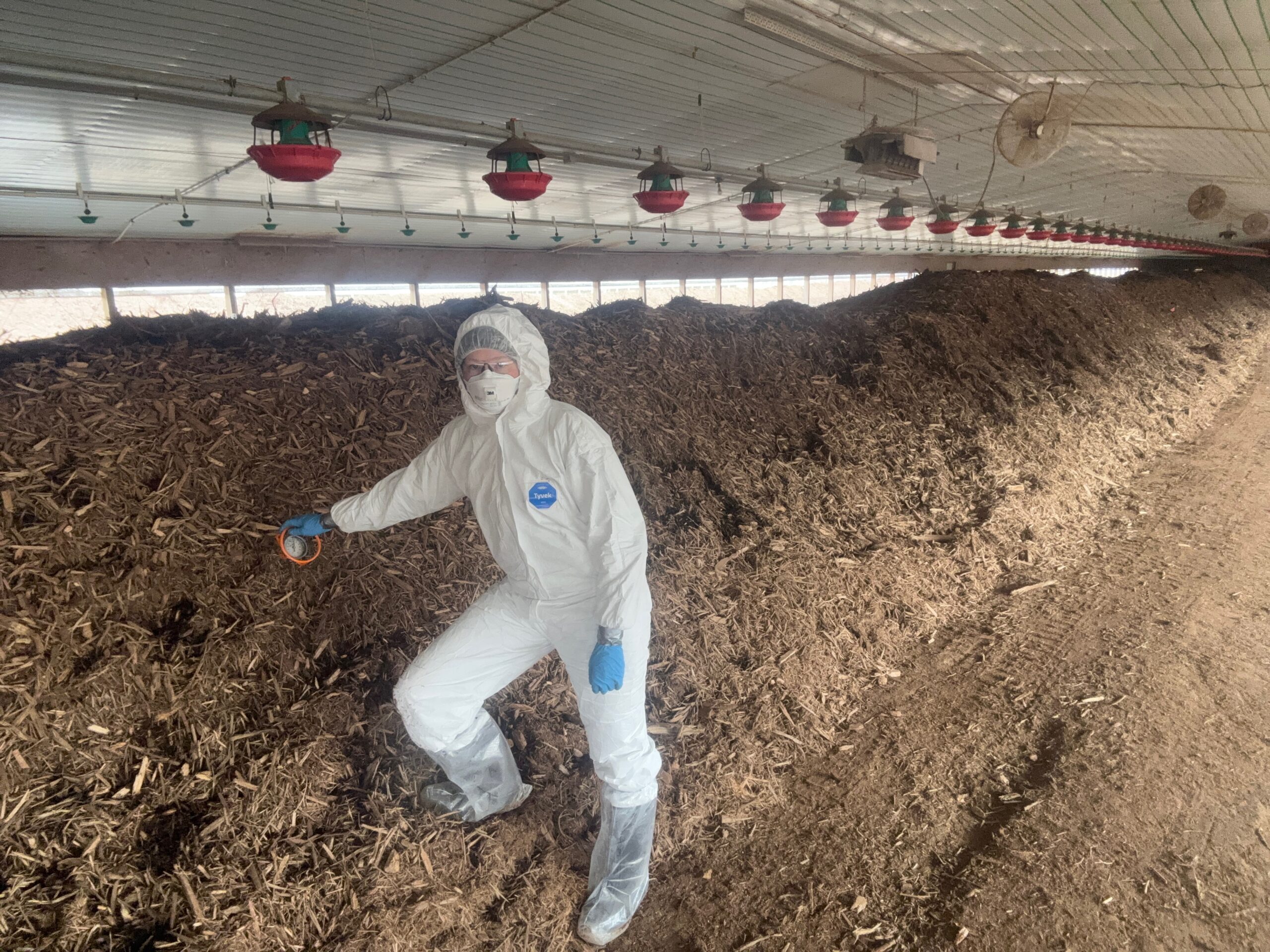 Person wearing a full-body white body suit and face mask for protection.