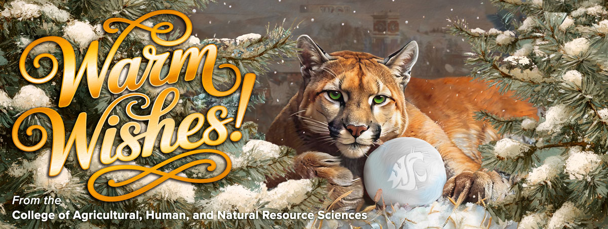 Cougar laying in the snow next to a snow covered tree with the words Warm Wishes.