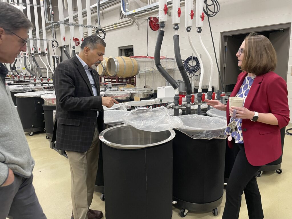 Three people stand next to equipment in the WSU Wine Science Center.