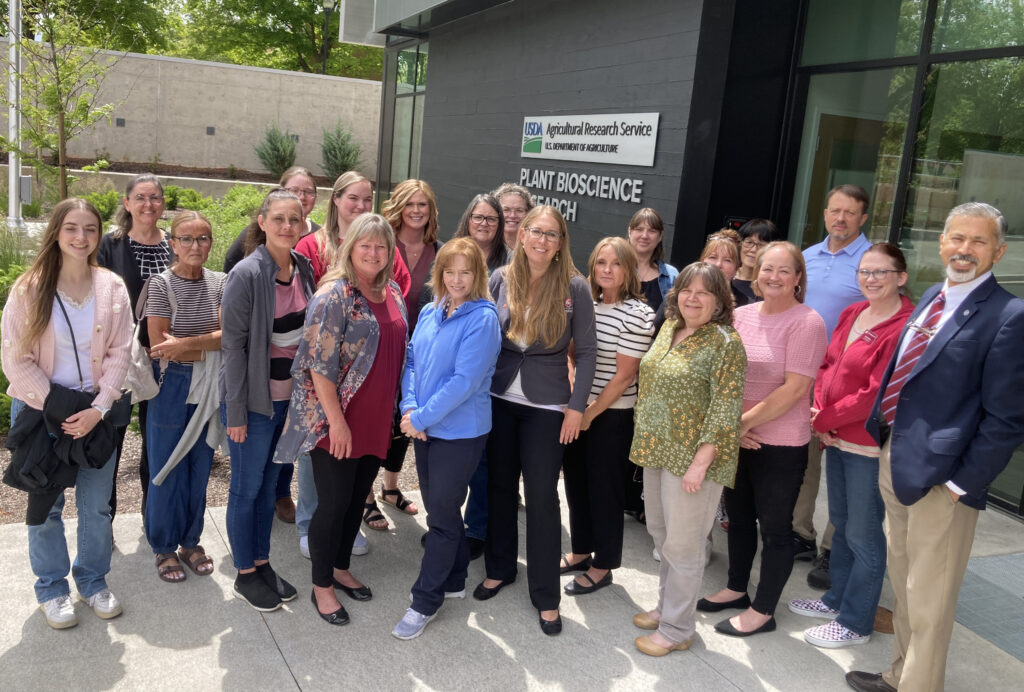 A group of 21 people stands outside of the new USDA-ARS Plant Bioscience Research Building.