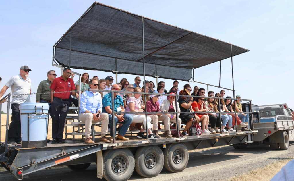 A large group sits on bleachers attached to the back of a pickup truck.