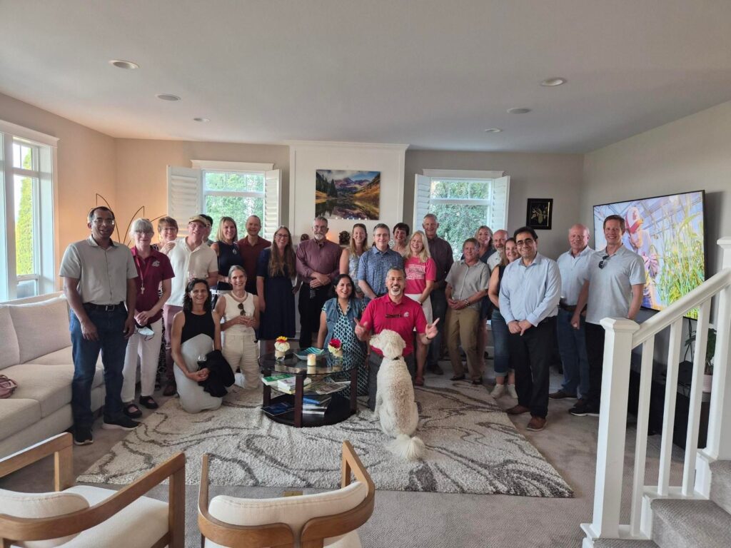 Approximately two dozen people and a dog pose for a group photo in a living room.