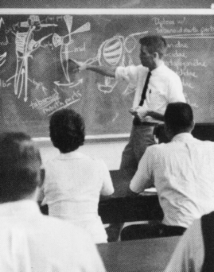 Catts during a lecture. He points to a diagram on a chalkboard.