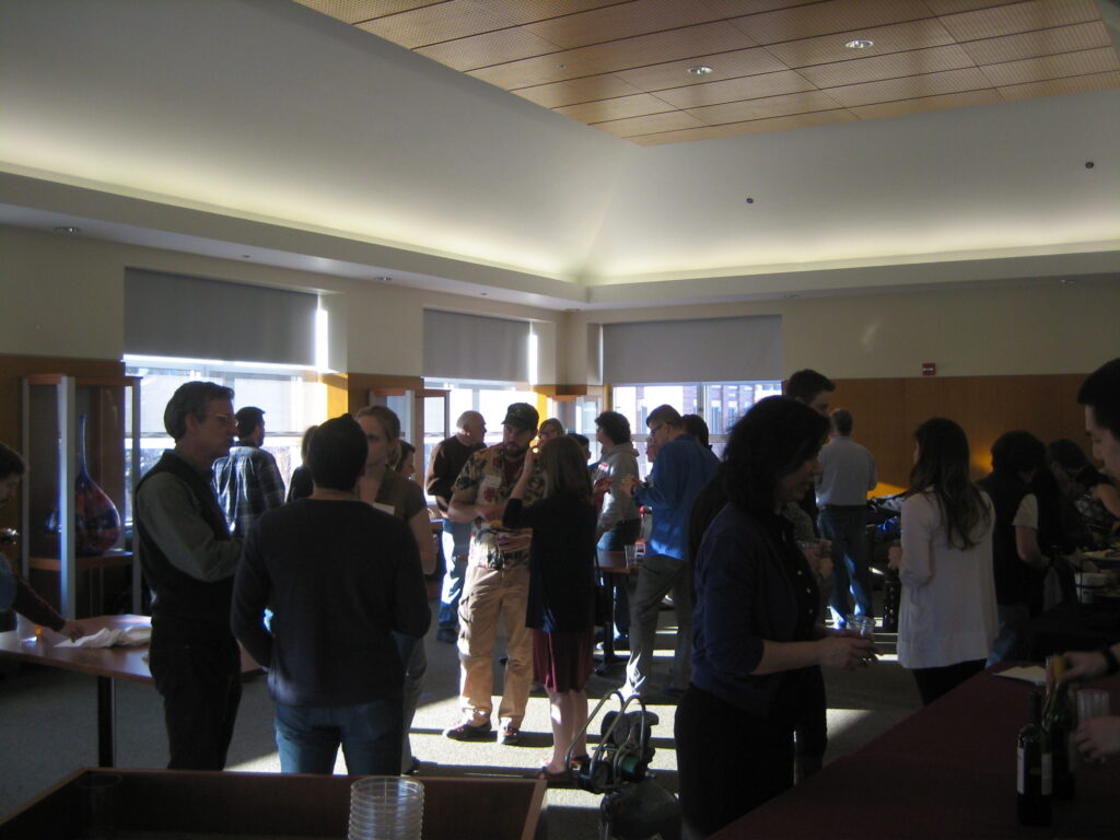 People are gathered together in large room, talking amongst themselves.