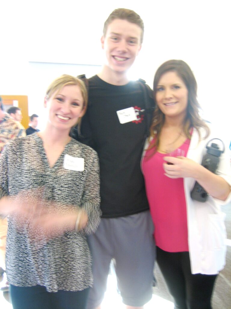 Three people stand together and smile for a picture.
